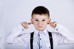 Angry unhappy irritated little boy covering ears